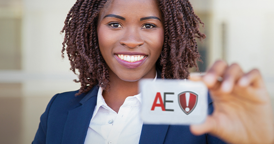 A woman smiling at the camera is holding up an "AE" badge.
